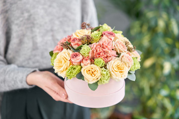 European floral shop. Floral bunch in round box. Bouquet of beautiful Mixed flowers in woman hand. Excellent garden flowers in the arrangement , the work of a professional florist.