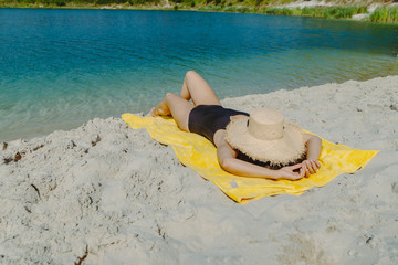 woman laying on yellow blanket sunbathing at sand beach