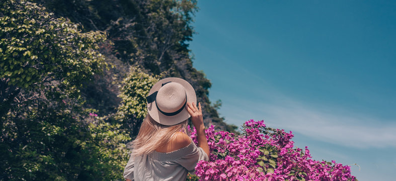 Beautiful blonde woman back view walks and admires tropical landscapes at paradise island hotel in Sanya, China. Luxury vacation resort concept, panoramic banner. Asia travel lifestyle tourist