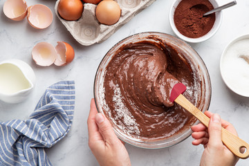 close up of female hands mixing ingredients in bowl. Baking chocolate cake - 304010526