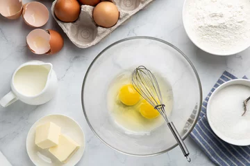 Tuinposter baking cake ingredients (eggs, flour, sugar, butter and milk) on white table © anna_shepulova