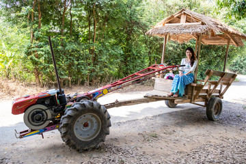 Asian woman sitting on The local farmer vehicle for travel in local. Thai language is E-tan car.