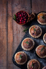 Fresh homemade Cranberry muffins in baking form on wooden table with Christmas decoration. Muffins in eco-friendly recyclable paper packaging. Selective focus, copy space.