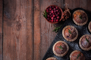 Fresh homemade Cranberry muffins in baking form on wooden table with Christmas decoration. Muffins in eco-friendly recyclable paper packaging. Selective focus, copy space.