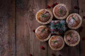 Fresh homemade Cranberry muffins in baking form on wooden table with Christmas decoration. Muffins in eco-friendly recyclable paper packaging. Selective focus, copy space.