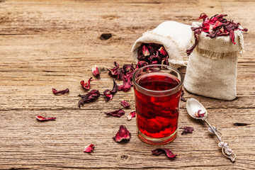 Hot hibiscus tea. Dry petals, linen sacks. Healthy food and self-care concept. Old wooden boards backgrounds © FuzullHanum