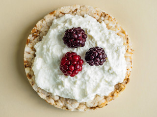 Cottage cheese and blackberries on crispy bread. Yellow background