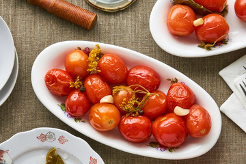 Pickled tomatoes in a white plate on a textile background