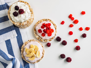 Crispbreads, cottage cheese and fruit on a white table. Striped kitchen towel