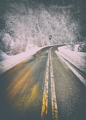 Empty asphalt road in snow covered spruce forest, beautiful colorful winter landscape. Vintage  look applied.