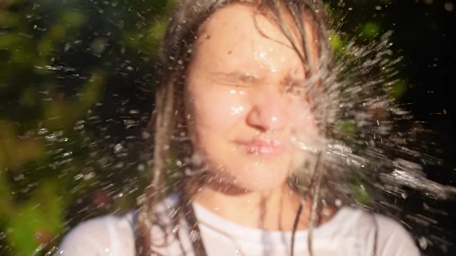 Closeup slow motion video of teenage girl closing eyes while water stream splashing in her face