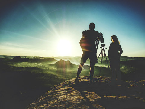 Couple tourist with photo camera at top of mountain watch sunset