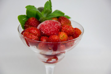frozen strawberries with mint leaves in a glass on a white background
