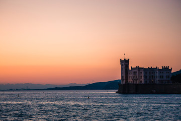 Naklejka premium Dramatic view of the tourist spot Castello di Miamare (Castle of Miramare) in Trieste, Italy on the Mediterranean sea coast in europe while sunset.