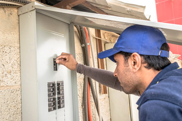 a professional electrician man is fixing the heavy unit of an air conditioner at the roof top of a building and wearing blue uniform and head cap