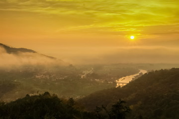 Mountain view panorama misty morning above Kok river and Tha Ton city in valley around with sea of mist and yellow sky background, sunrise at Wat Tha Ton, Fang, Chiang Mai, northern of Thailand.