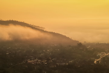Mountain view misty morning of the mist moving on top hill above Tha Ton city with yellow sun light in the sky background, sunrise at Wat Tha Ton, Chiang Mai, Thailand.