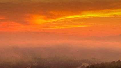Mountain view panorama misty morning of top hill around with soft mist with orange sun light in cloudy sky background, sunrise at Wat Tha Ton, Fang, Chiang Mai, Thailand.