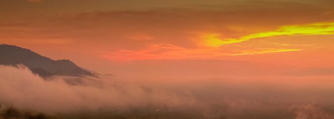 Mountain view panorama misty morning of top hill around with soft mist with orange sun light in cloudy sky background, sunrise at Wat Tha Ton, Fang, Chiang Mai, Thailand.