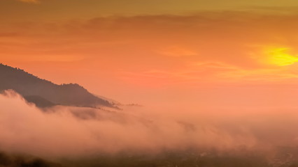 Mountain view panorama misty morning of top hill around with soft mist with orange sun light in cloudy sky background, sunrise at Wat Tha Ton, Fang, Chiang Mai, Thailand.