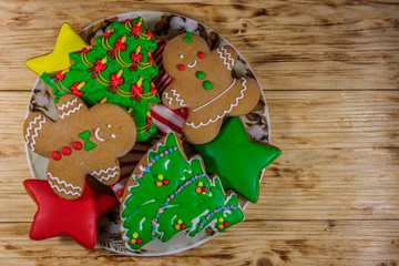 Plate with tasty festive Christmas gingerbread cookies on wooden table. Top view