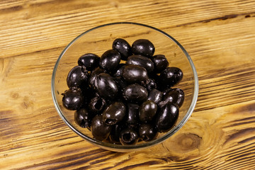 Pickled black olives in glass bowl on wooden table