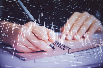 Forex graph on hand taking notes background. Concept of research. Double exposure