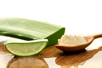 Aloe vera plant and aloe gel on wooden spoon, isolated on white background, closeup.