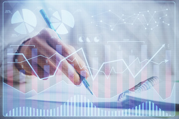 Financial forex graph displayed on hands taking notes background. Concept of research. Double...