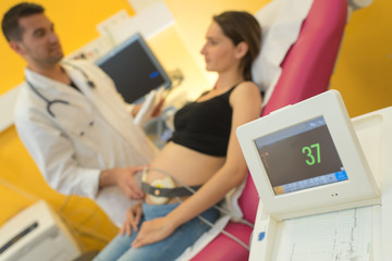 gynecologist showing ultrasound photo to pregnant woman