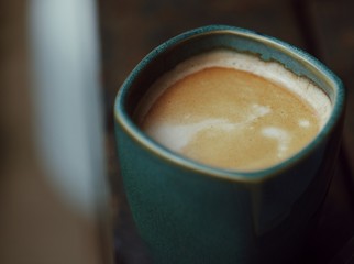 A blue cup of coffee without handle. Espresso closeup. Outdoor photography. Magical morning. Coffee with milk and foam. 100% Arabica. romantic breakfast
