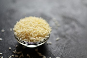 Different cereals are scattered on a dark table. Rice, wheat and other groats