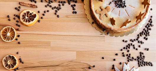 Christmas homemade cheesecake with gingerbread man and stars on a wooden table with coffee beans and copy space. Panoramic banner top view.