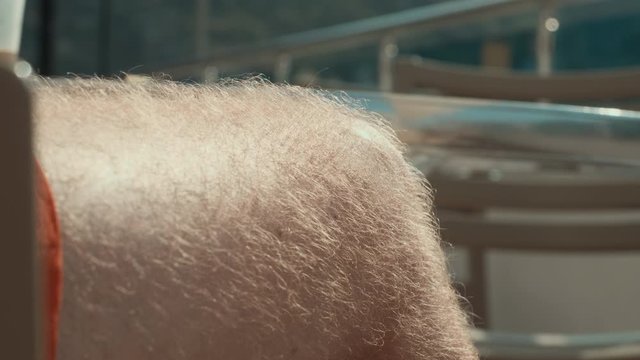 Close up male hairy leg in summer shorts at sunny day. Man with hairy legs tanning in beach shorts on sun at summer day
