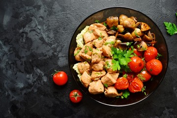 Tomatoes, chicken and mushrooms in a white plate on a dark background. Grilled tomatoes, fried champignons and grilled chicken. Vegetables and meat.