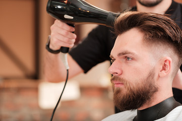 Fashionable man with a beard makes hair styling