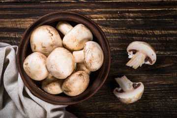 Mushrooms in a bowl at wooden table.