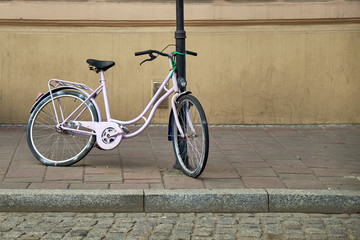 Fototapeta na wymiar Pink bike parked near to the lamp post. Healthy lifestyle, conviniet transport, environment protection, green energy