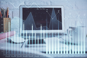 Stock market graph on background with desk and personal computer. Double exposure. Concept of financial analysis.