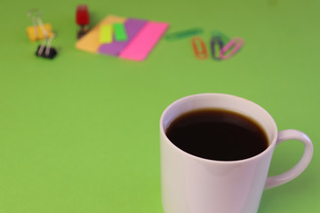 coffee cup in a green desk neon post-it notes and clips photography