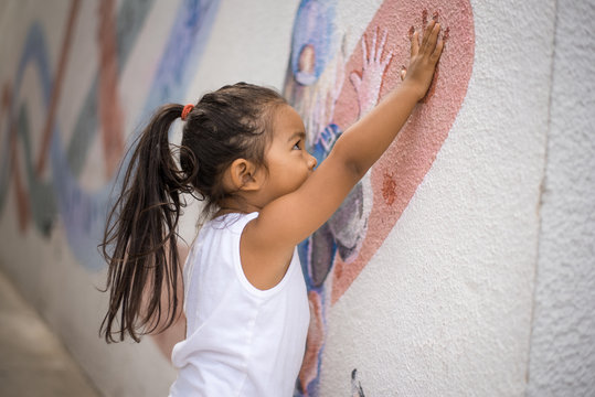 Little Girl Putting Her Hand on a Wall Painting