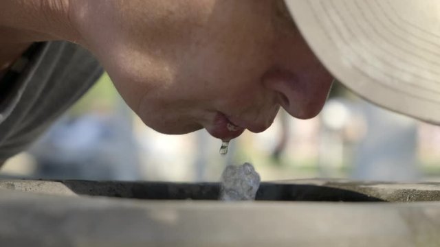 Woman drinks spring water from city fountain closeup.