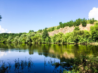 Fototapeta premium Blue sky with clouds above the trees in green forest