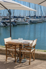 Fototapeta na wymiar chairs and a table on the Mediterranean coast in the recreation area of ​​the port of the Italian capital