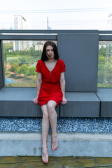 girl in a red dress sits on the roof of a building with a city view