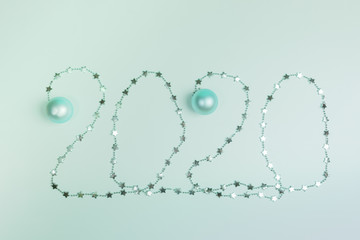 Christmas festive layout in trendy Neo Mint color: numbers 2020 of shiny garland with small stars and Christmas balls. 