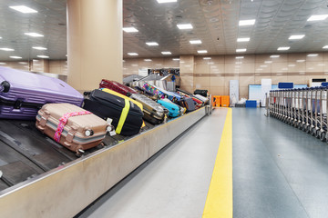 Luggage conveyor belt and row of trolleys in airport