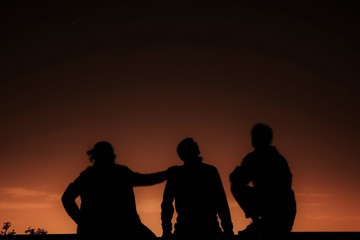 Fototapeta na wymiar Silhouette of three men looking at the sky at night