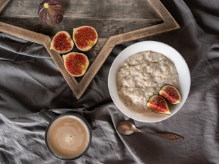 Fototapeta na wymiar Healthy breakfast in bed. Coffee, porridge with figs, on a rustic wooden board. Clean food, alkaline diet, 