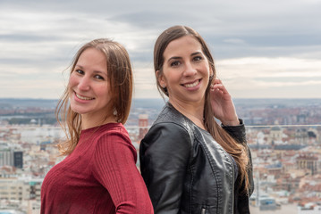 A couple of women smiling and looking at camera with the city in the background